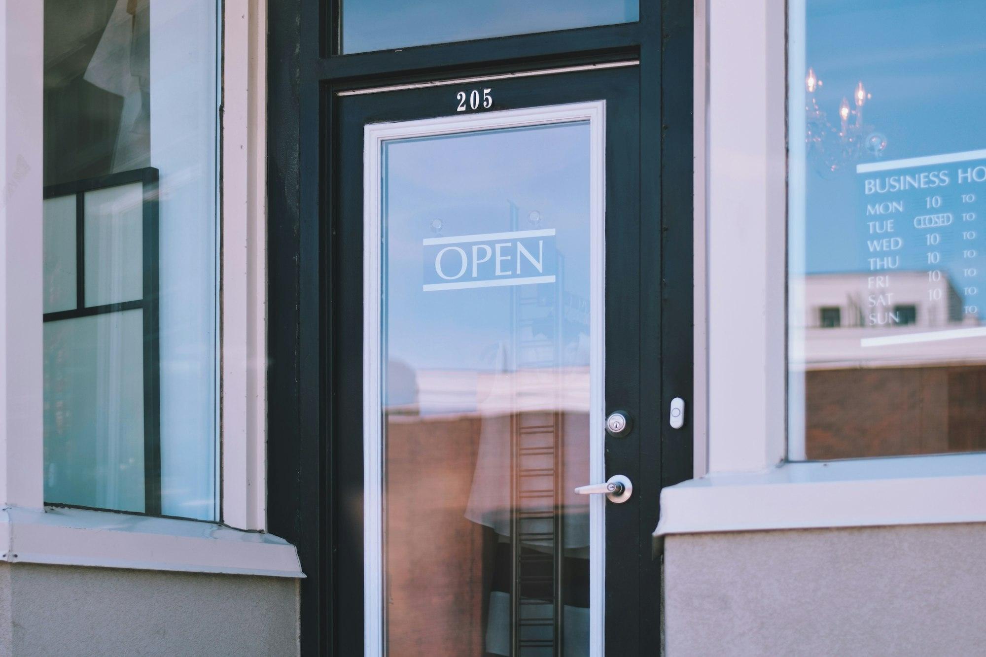 Entrance to a small boutique shop with an Open sign on a door